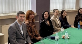 Grupa ludzi siedzi przy stole, przeglądając dokumenty i rozmawiając ze sobą