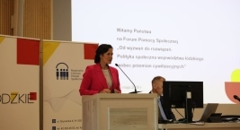 Zdjęcie przedstawia osobę przemawiającą przy mównicy podczas Forum Pomocy Społecznej