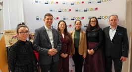 Ludzie zgromadzeni przed dużym banerem, wyrażają radość i entuzjazm.  