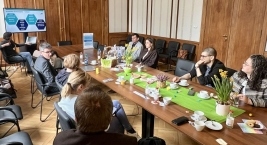 Osoby siedzące przy stole w sali spotkań, prowadzące rozmowę