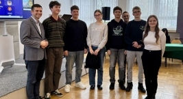 Zespół młodych osób pozujący do zdjęcia przed ekranem